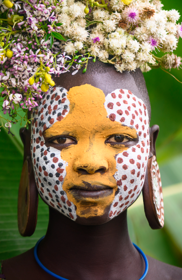 Chica africana con motivos tribales pintados en el rostro y flores en la cabeza